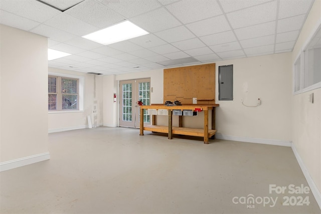 basement with electric panel, a paneled ceiling, and french doors