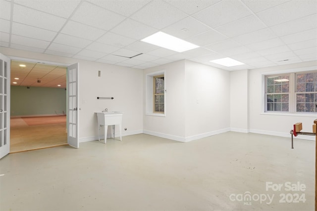 basement with a drop ceiling and french doors