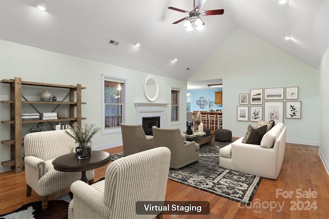 living room with hardwood / wood-style flooring, ceiling fan, and high vaulted ceiling