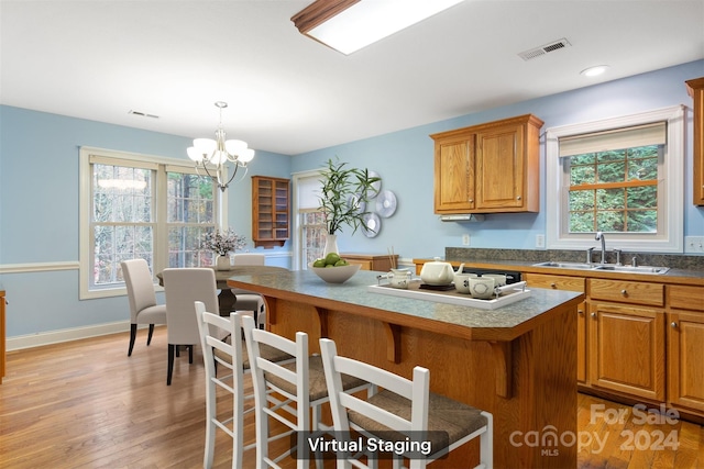 kitchen featuring an inviting chandelier, sink, hanging light fixtures, light hardwood / wood-style flooring, and a kitchen island