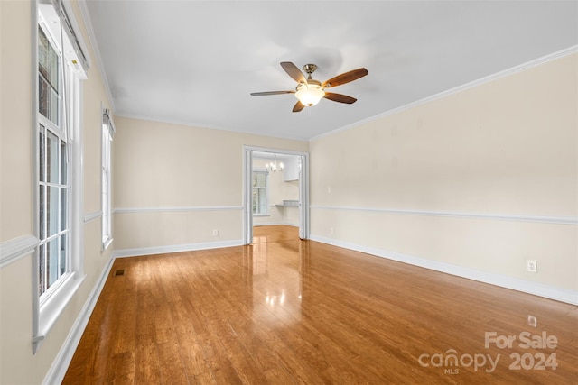 empty room featuring crown molding, hardwood / wood-style floors, and ceiling fan with notable chandelier