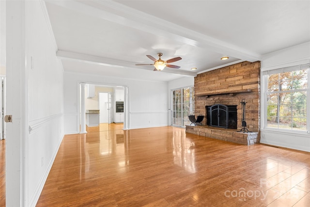 unfurnished living room with ceiling fan, a fireplace, wood-type flooring, and ornamental molding