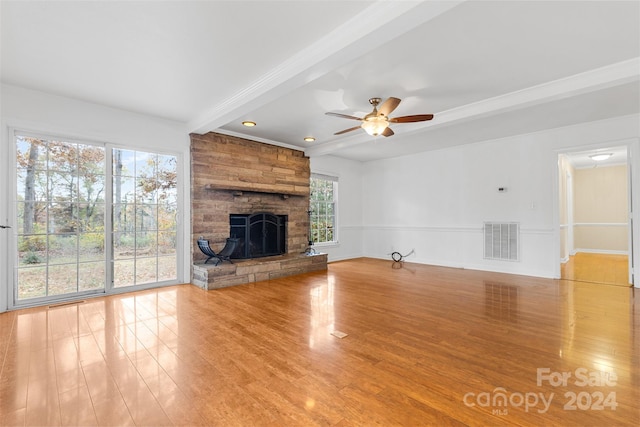 unfurnished living room featuring plenty of natural light, light hardwood / wood-style floors, beam ceiling, and a fireplace