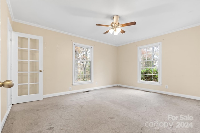 spare room with light colored carpet, a wealth of natural light, ornamental molding, and ceiling fan