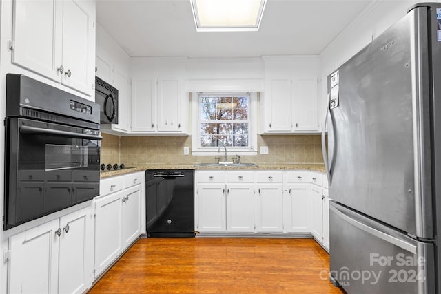 kitchen featuring black appliances, sink, decorative backsplash, light hardwood / wood-style floors, and white cabinetry