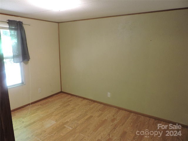 spare room with light wood-type flooring and ornamental molding