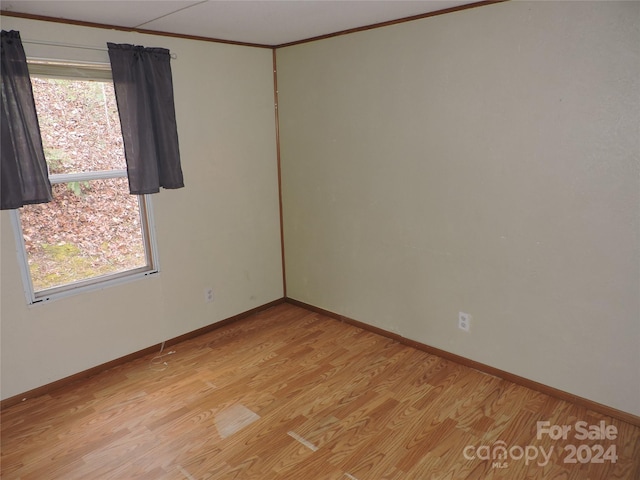 empty room featuring light hardwood / wood-style flooring, a healthy amount of sunlight, and crown molding