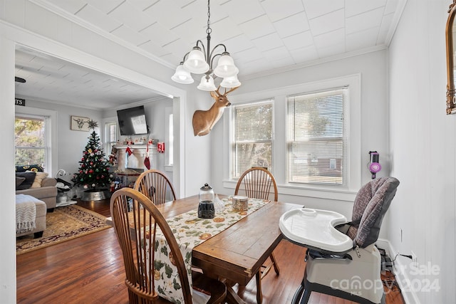 dining space with wood-type flooring, a notable chandelier, and ornamental molding