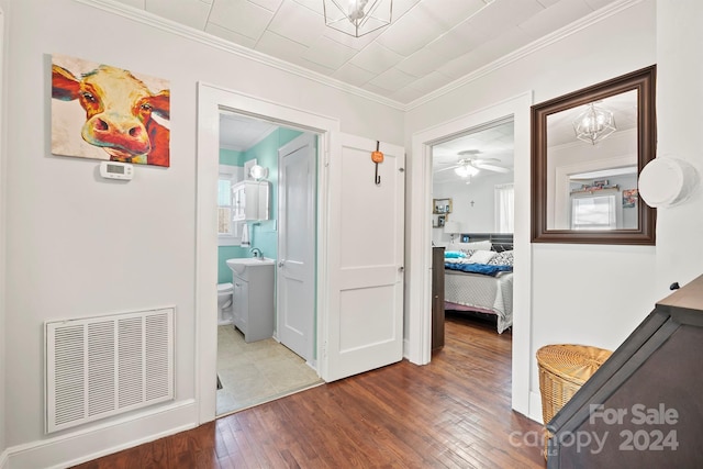 hallway with sink, ornamental molding, and dark wood-type flooring