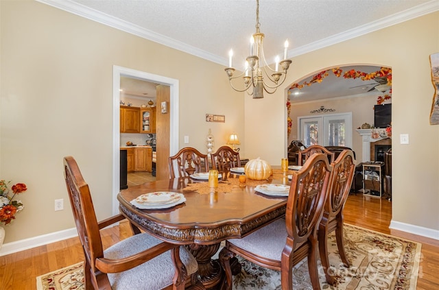 dining room featuring french doors, a textured ceiling, light hardwood / wood-style floors, and crown molding