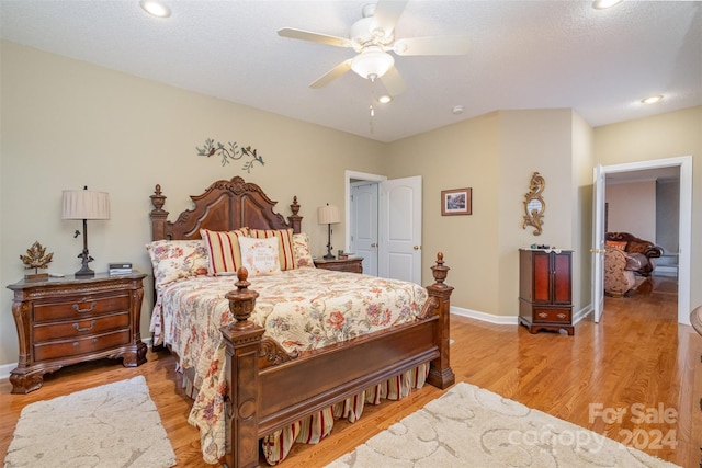 bedroom with ceiling fan, light hardwood / wood-style floors, and a textured ceiling