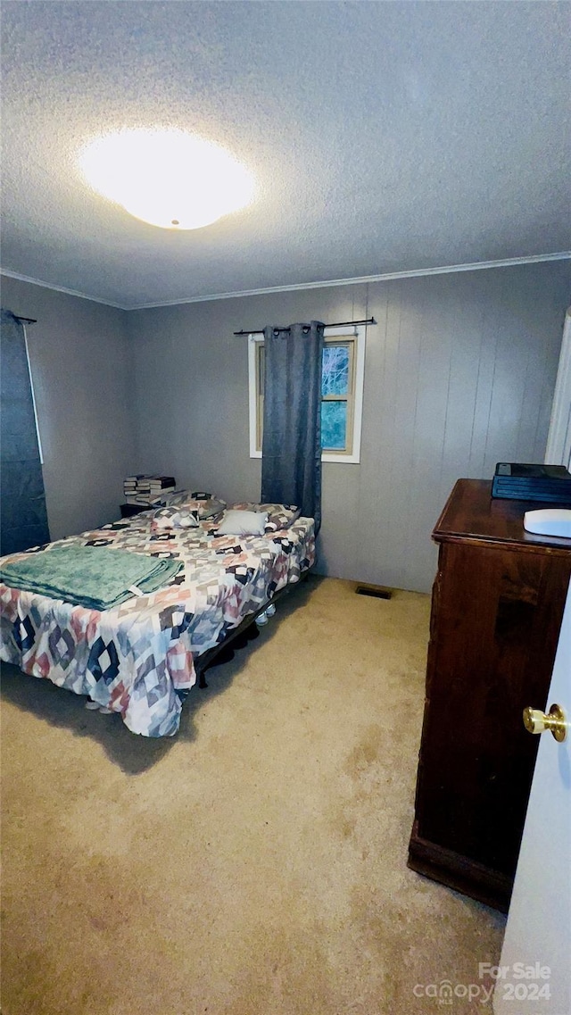 carpeted bedroom with ornamental molding and a textured ceiling