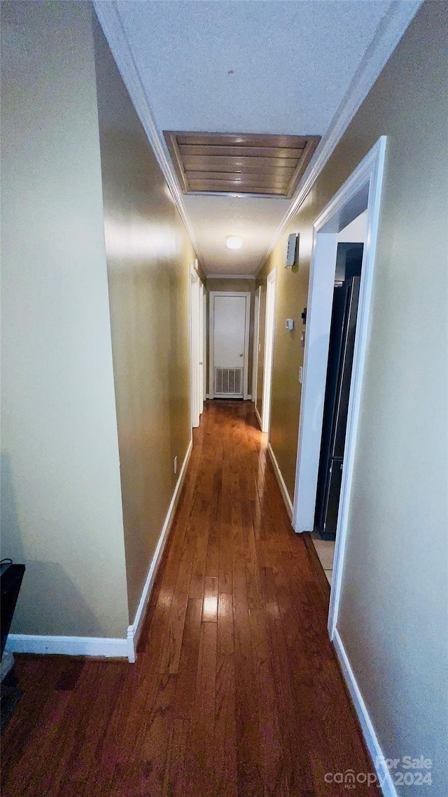 corridor featuring ornamental molding and dark wood-type flooring