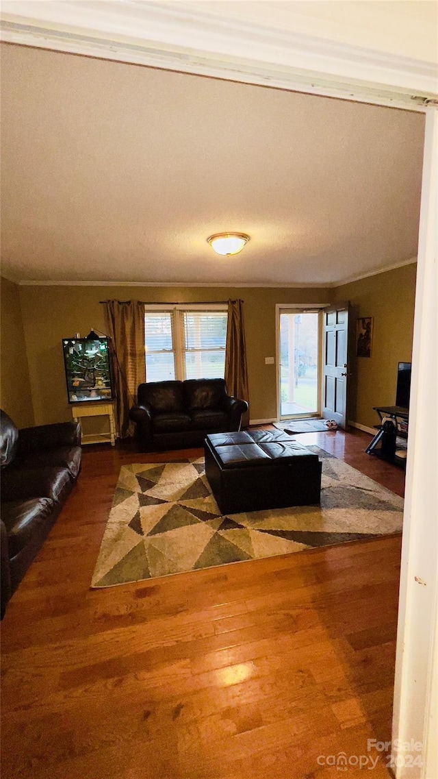 unfurnished living room featuring hardwood / wood-style flooring and ornamental molding