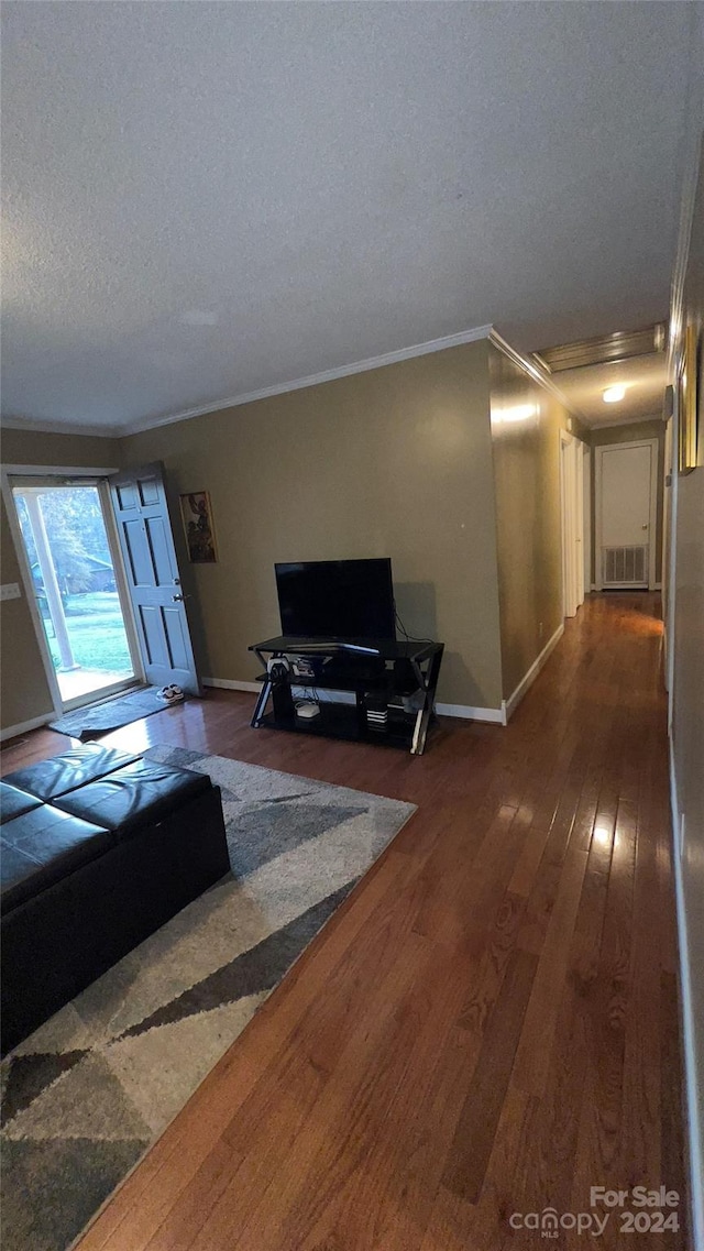 living room featuring a textured ceiling, dark hardwood / wood-style flooring, and ornamental molding