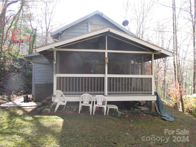 rear view of house featuring a sunroom and a yard