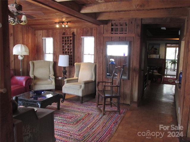 living room with beam ceiling, an AC wall unit, ceiling fan, and a healthy amount of sunlight