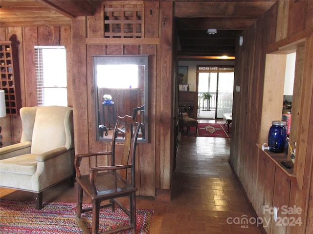 interior space with beamed ceiling, dark parquet flooring, and wood walls