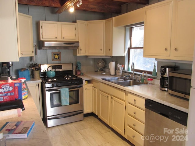 kitchen featuring beam ceiling, sink, light tile patterned floors, and appliances with stainless steel finishes