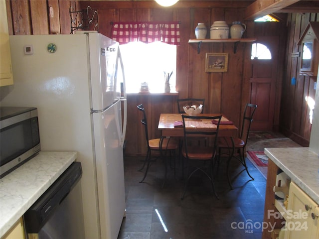 kitchen with wooden walls, plenty of natural light, and stainless steel appliances