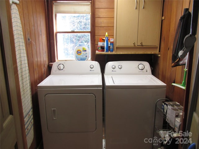 laundry room with cabinets, wooden walls, and washer and dryer