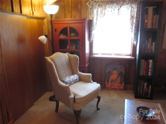 sitting room with light colored carpet and wooden walls