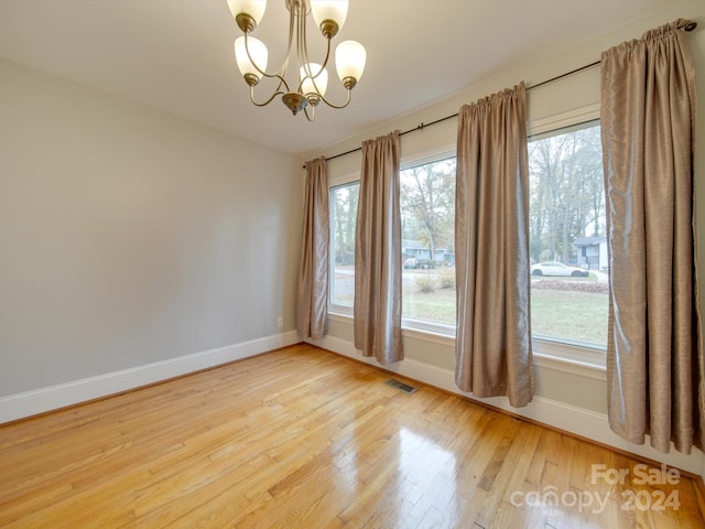 unfurnished room featuring a notable chandelier and wood-type flooring