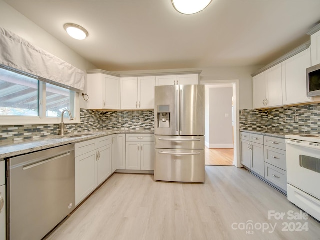 kitchen with backsplash, sink, light wood-type flooring, white cabinetry, and stainless steel appliances