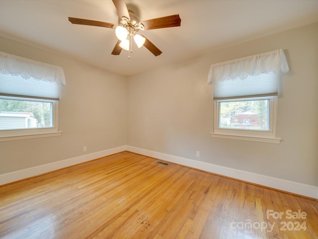 empty room with ceiling fan, a healthy amount of sunlight, and light hardwood / wood-style floors