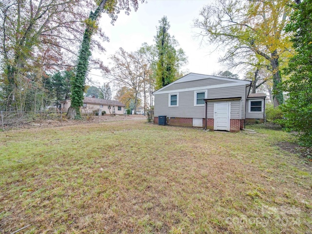 rear view of house featuring cooling unit and a lawn