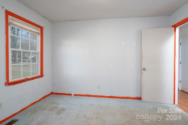 unfurnished room featuring a textured ceiling and light carpet