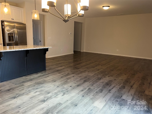 kitchen featuring white cabinets, hanging light fixtures, stainless steel fridge, light stone countertops, and dark hardwood / wood-style flooring