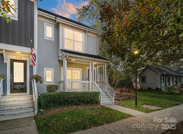 townhome / multi-family property with a yard, board and batten siding, and a porch