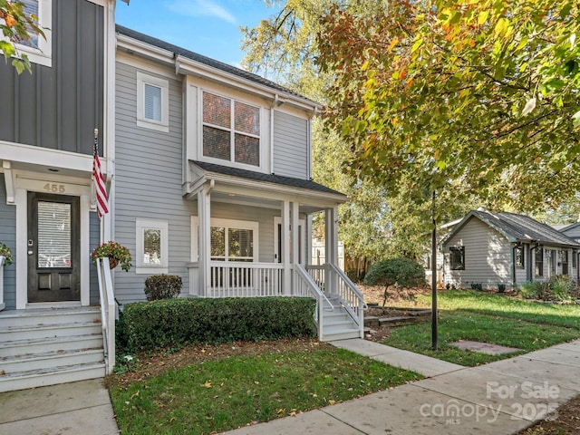 view of property with a porch and a front lawn