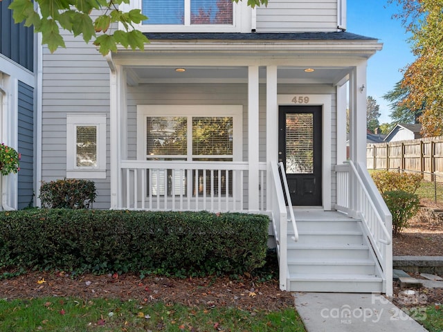 doorway to property with fence and covered porch