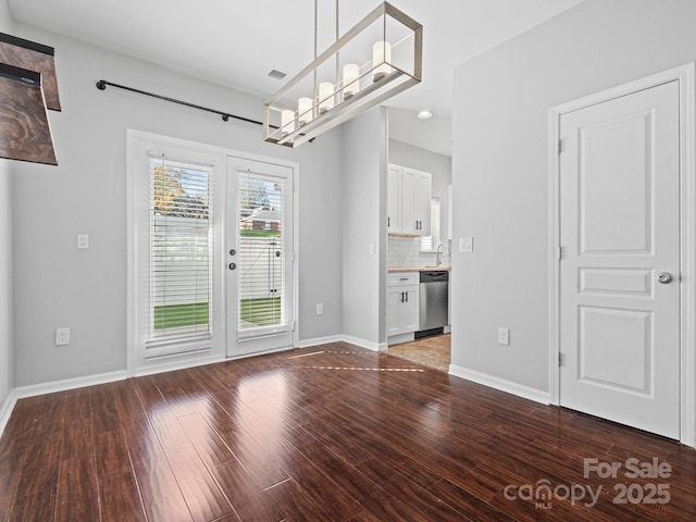 unfurnished dining area featuring french doors, baseboards, visible vents, and wood finished floors