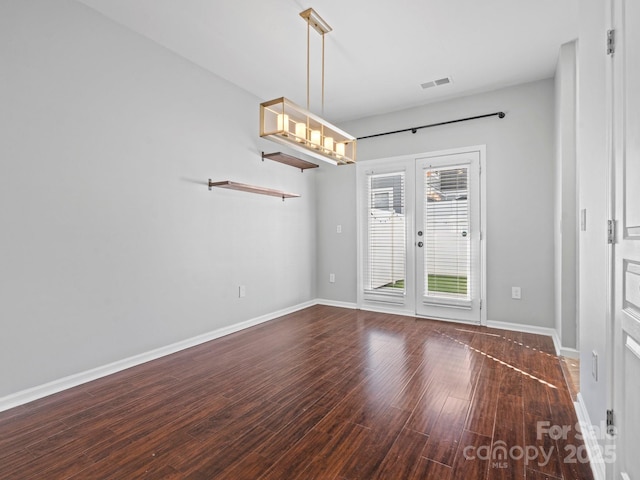 empty room with wood finished floors, visible vents, french doors, and baseboards