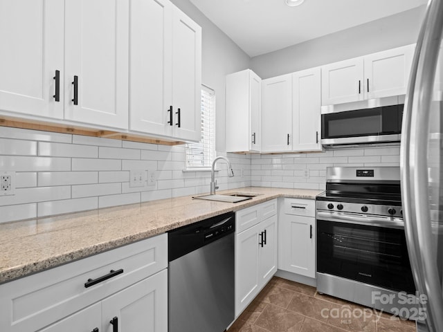 kitchen with a sink, white cabinetry, backsplash, and stainless steel appliances