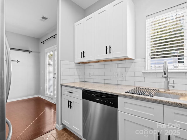 kitchen featuring visible vents, decorative backsplash, appliances with stainless steel finishes, white cabinetry, and a sink