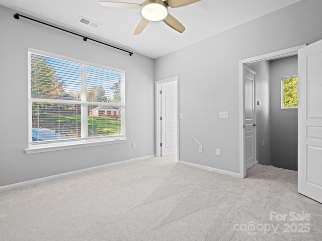 unfurnished bedroom featuring ceiling fan, light colored carpet, visible vents, and baseboards