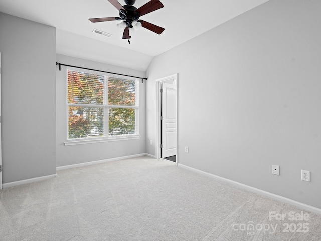 carpeted spare room featuring visible vents, baseboards, a ceiling fan, and vaulted ceiling