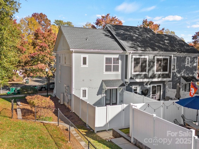 back of property featuring a fenced backyard and a shingled roof