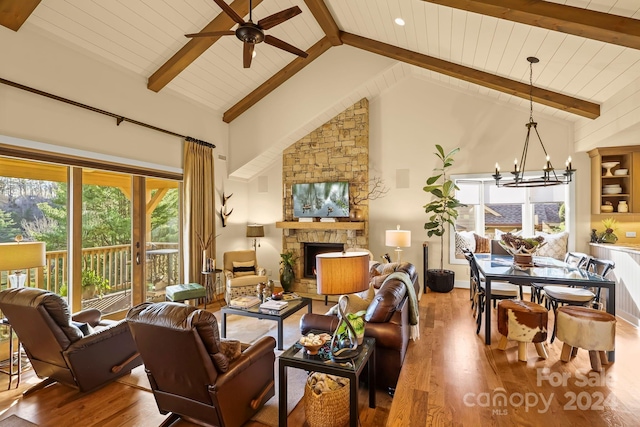 living room featuring hardwood / wood-style floors, high vaulted ceiling, ceiling fan with notable chandelier, a fireplace, and beamed ceiling