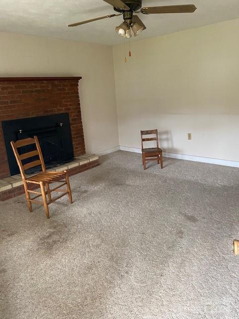 unfurnished room with carpet flooring, ceiling fan, and a fireplace