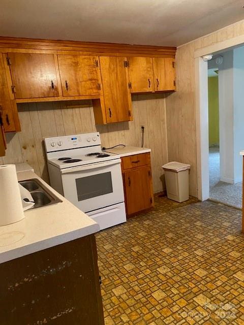 kitchen featuring electric stove, sink, and wooden walls