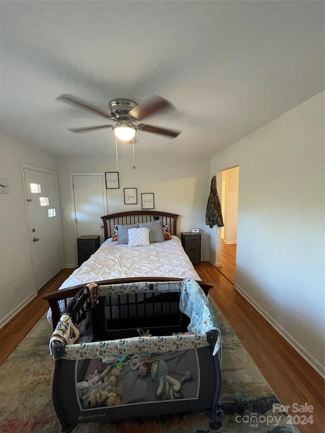 bedroom with hardwood / wood-style flooring, ceiling fan, and a textured ceiling