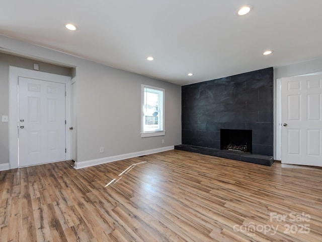 unfurnished living room featuring a tile fireplace and light wood-type flooring