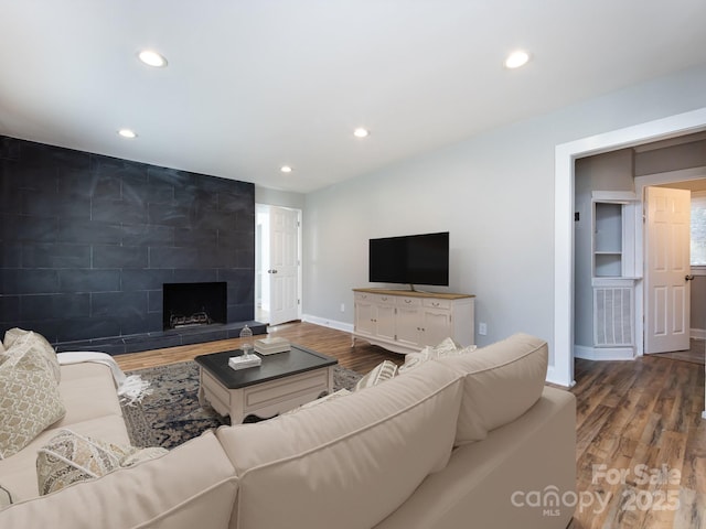 living room with a tile fireplace and hardwood / wood-style flooring