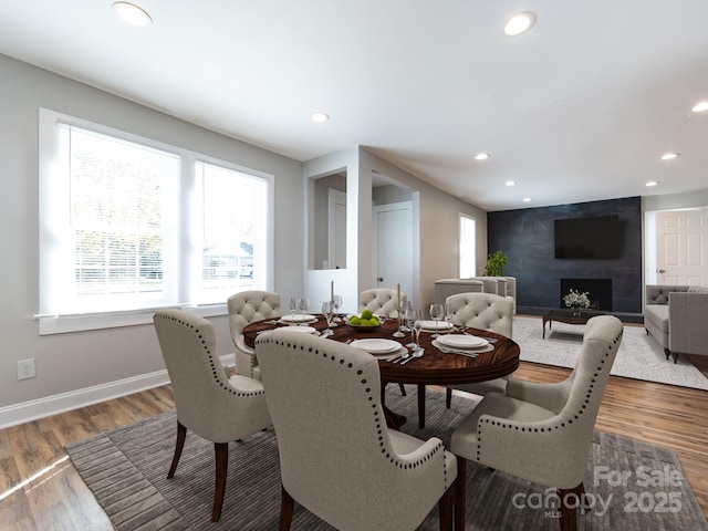 dining space with hardwood / wood-style floors and a fireplace