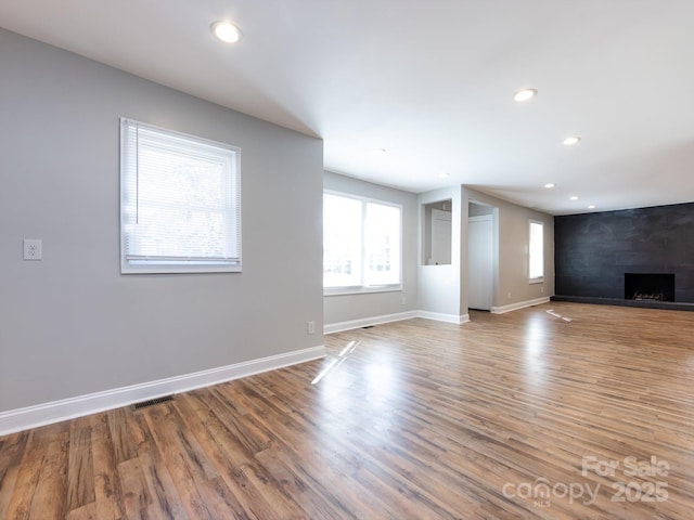 unfurnished living room featuring a tile fireplace and light hardwood / wood-style flooring